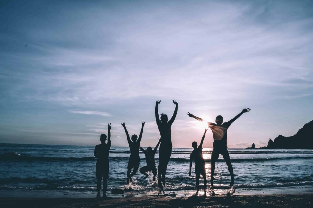 people jumping in joy at the coastline