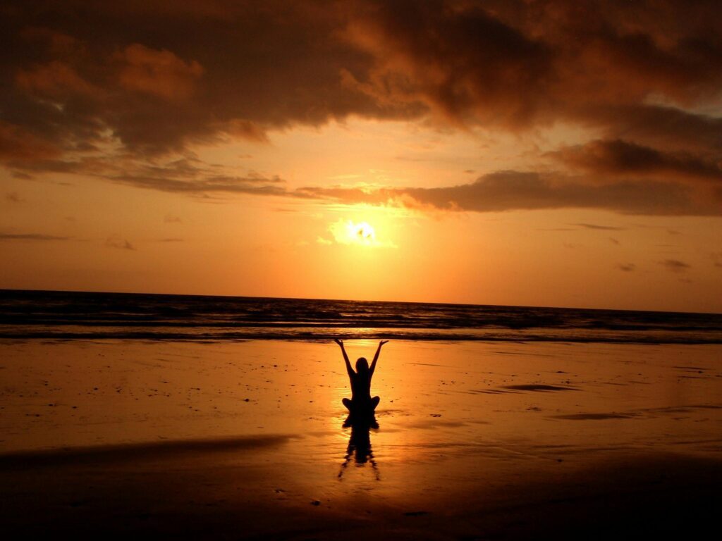 silhouette of person raising their hands during sunset