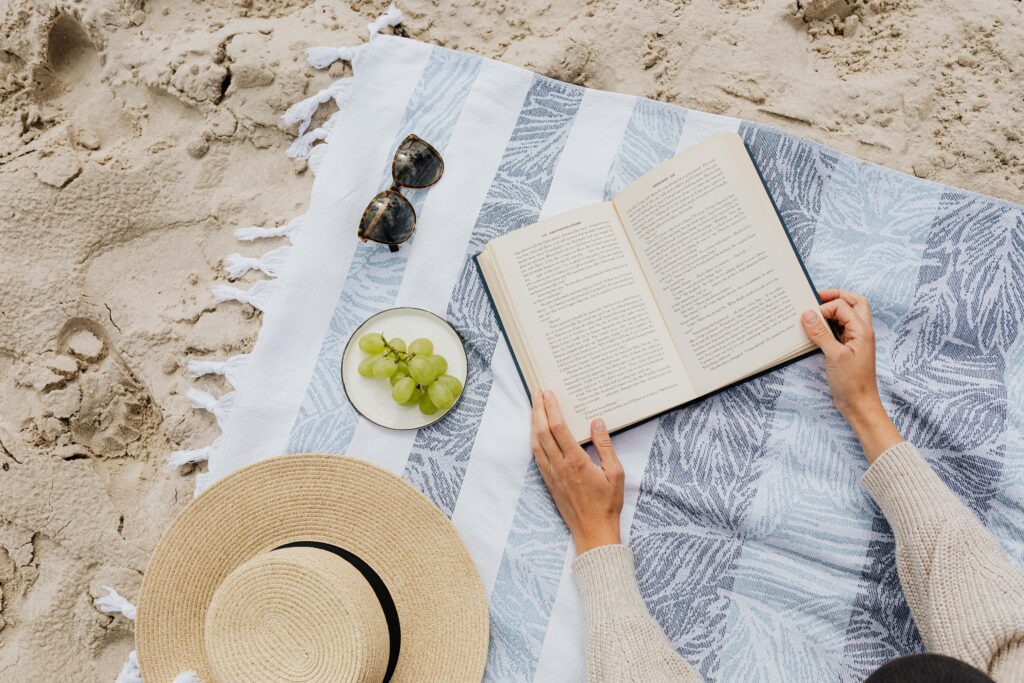 grapes, book and sun hat at the beach