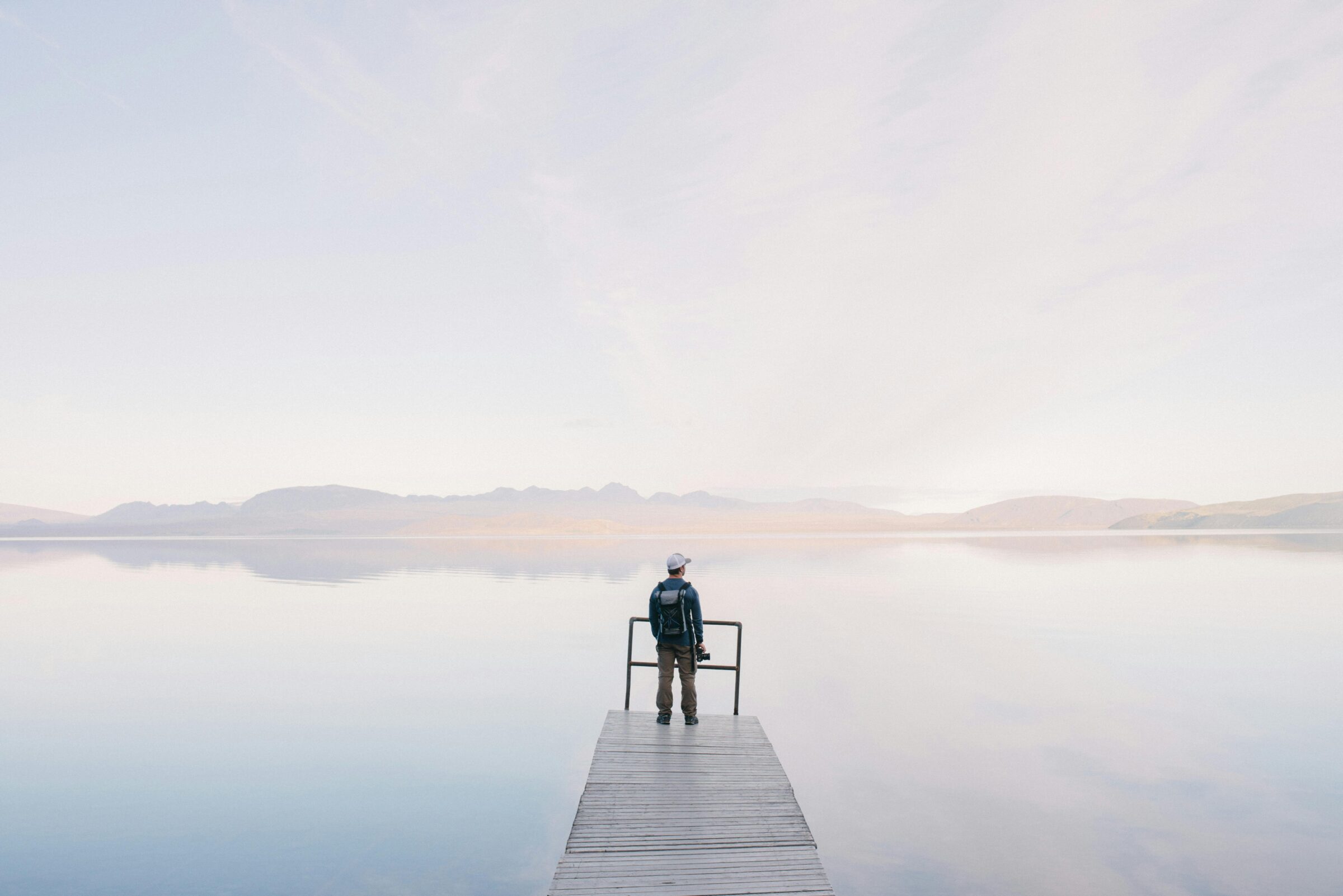 man in jacket standing at end of dock near water