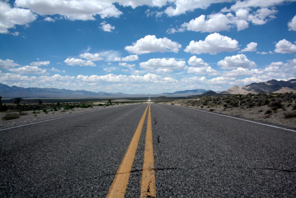 black top road under clear blue cloudy sky