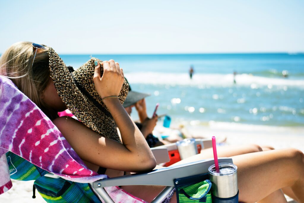 woman on sun chaise covering face with hat