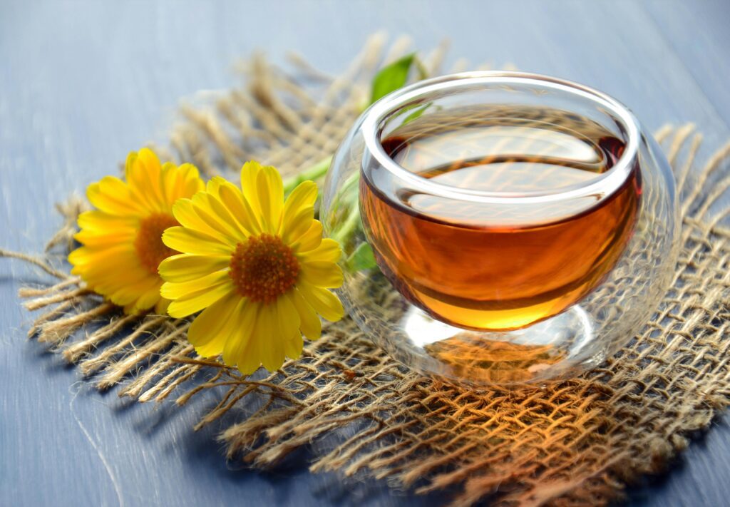 clear glass of tea next to yellow flowers