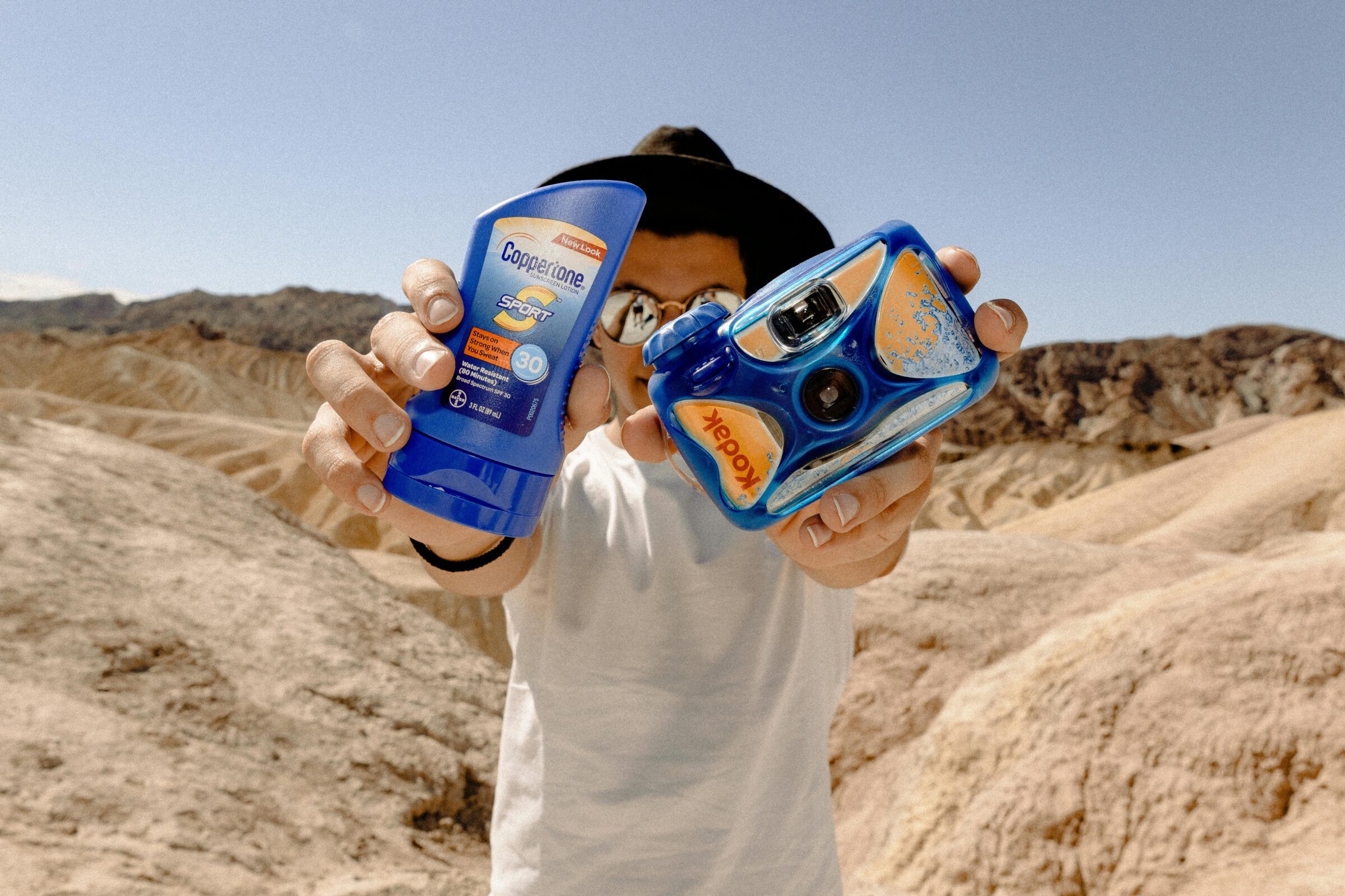 man holding kodak camera and sunscreen