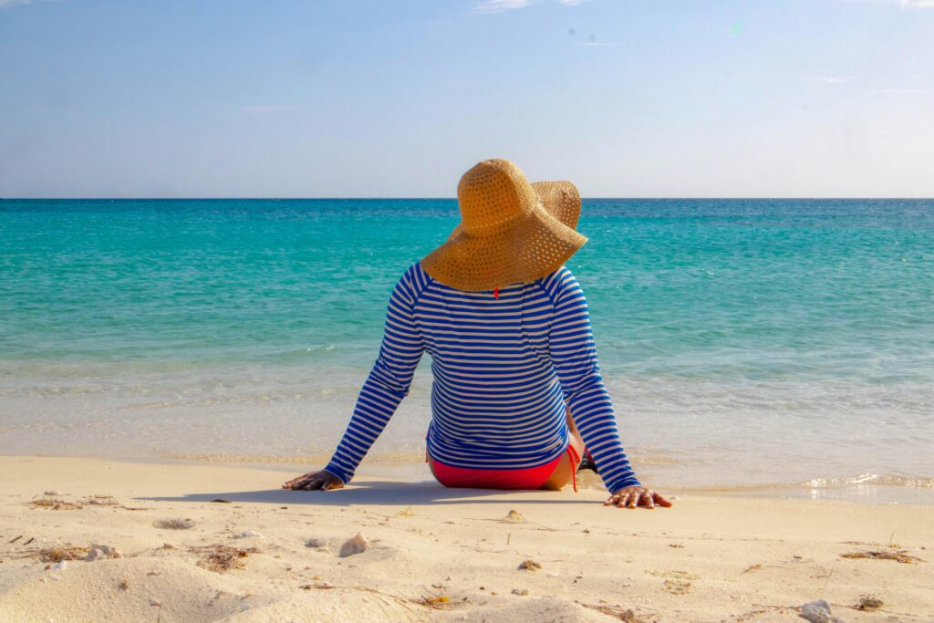 person wearing sun hat sitting on beach